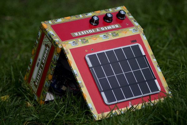 The amp on the grass, propped open with the solar panel facing the camera