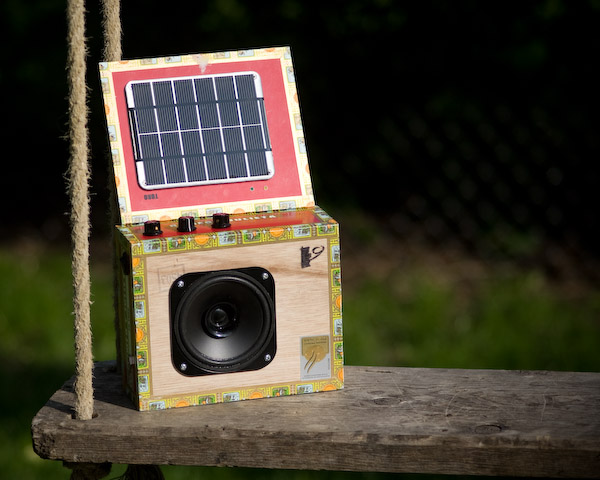 The solar stella, with the speaker facing the camera and the solar panel propped up to receive sunlight