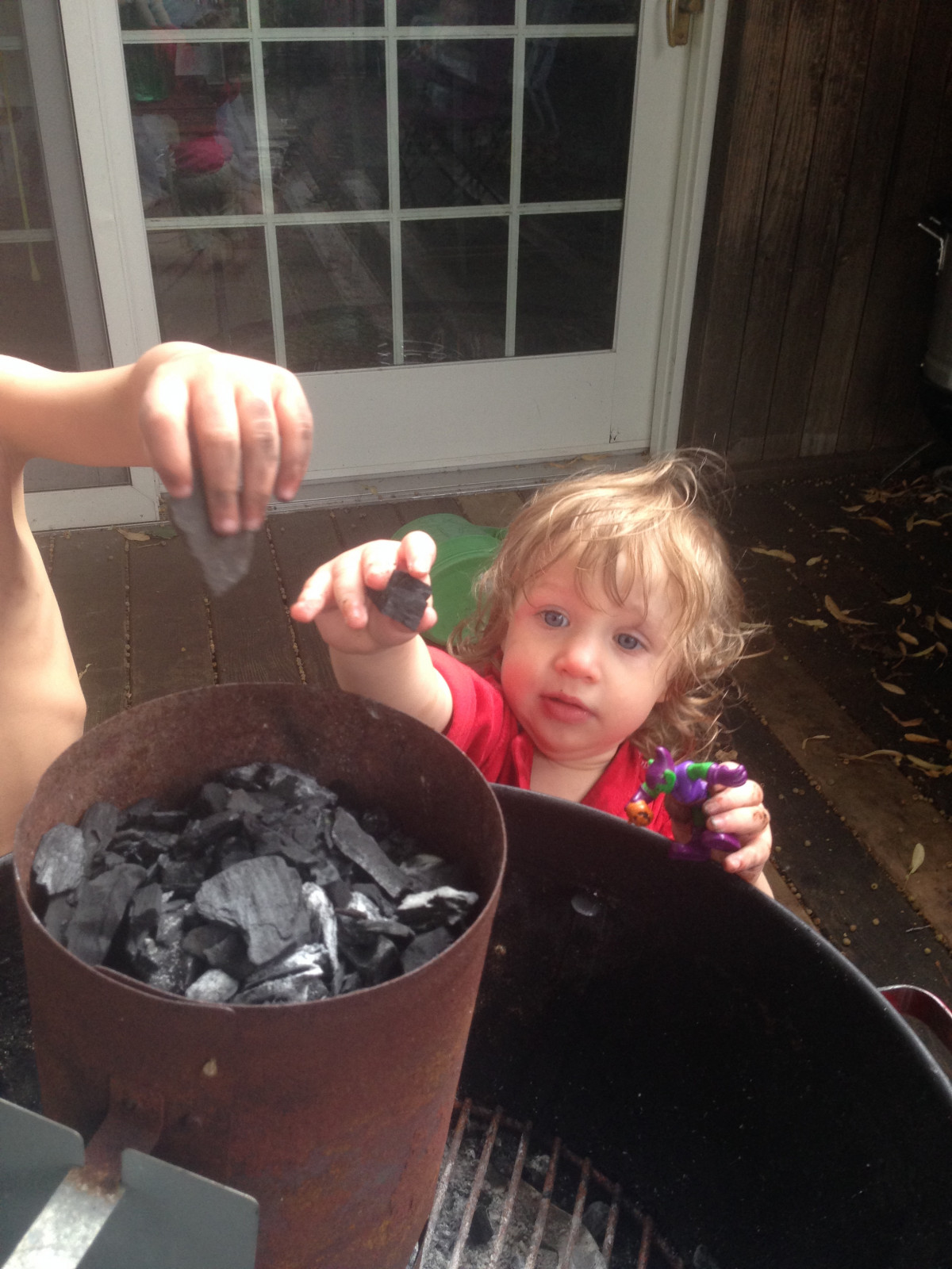 A little girl and a little boy putting charcoal pieces in a chimney starter