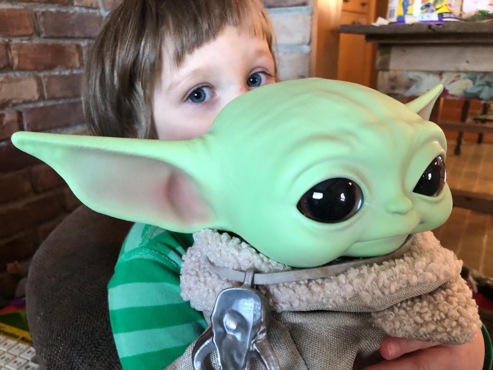 A child holding a doll of Baby Yoda