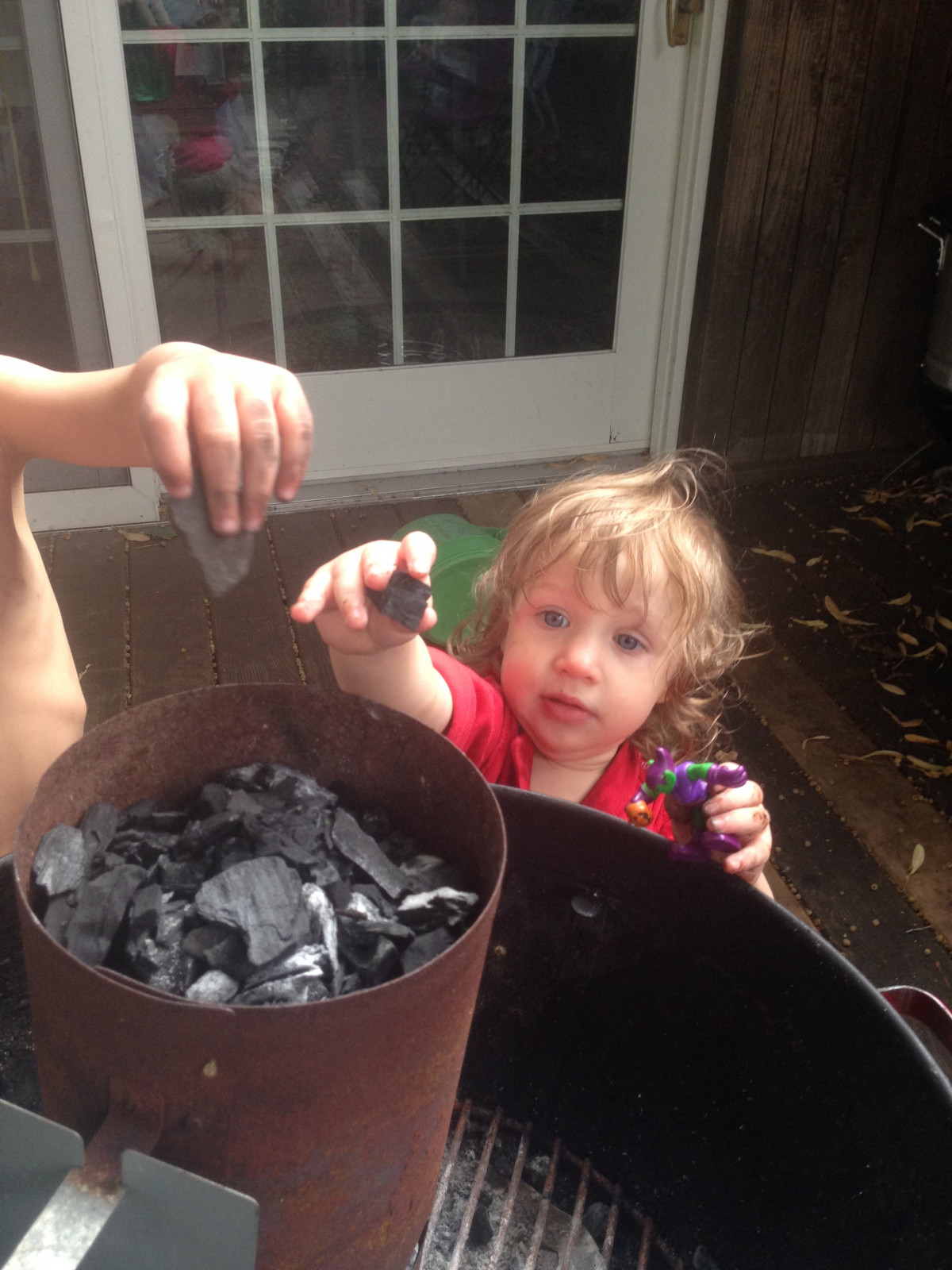 A little girl and a little boy putting charcoal pieces in a chimney starter