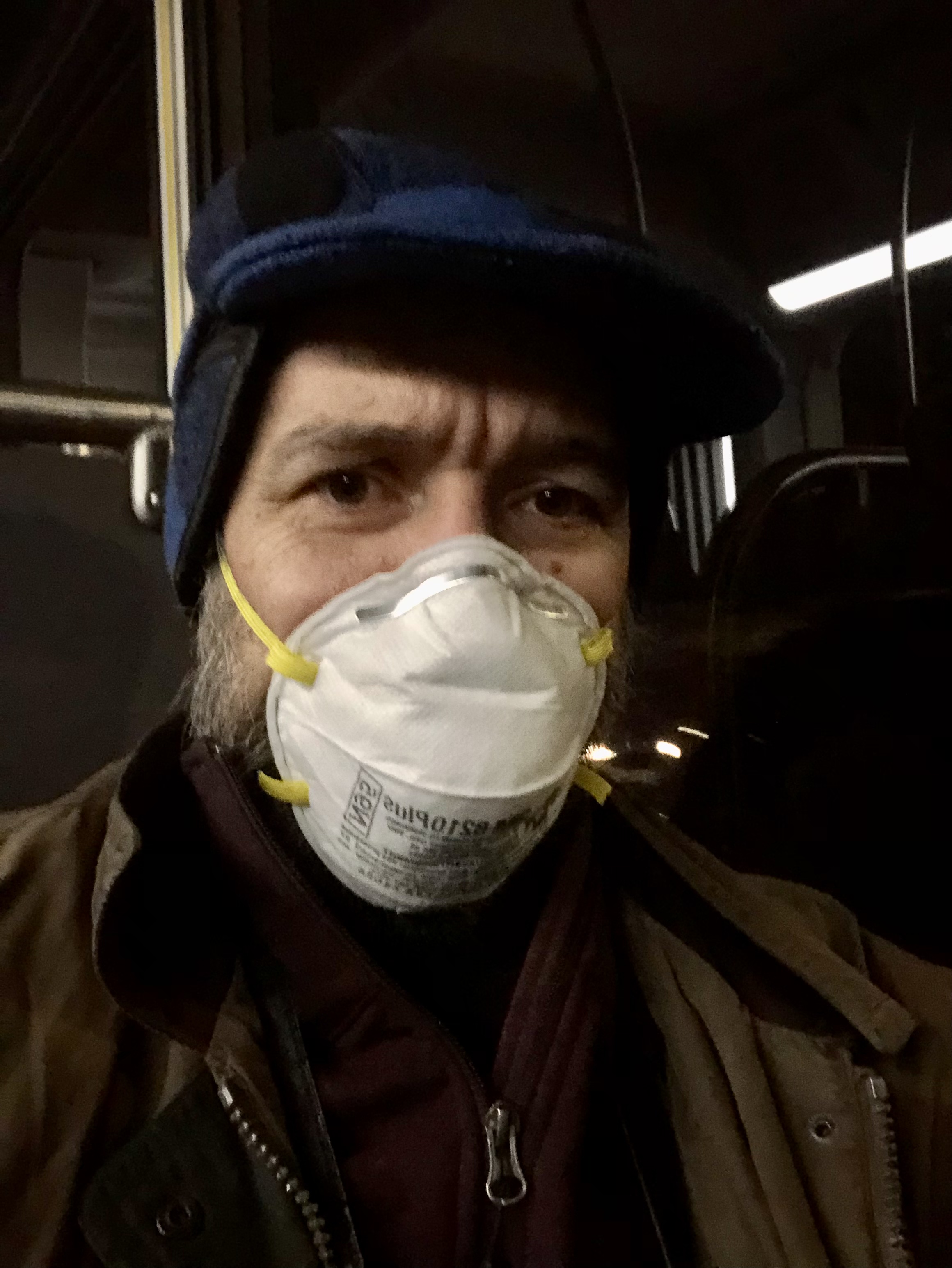 Me on the bus, wearing a mask and a blue hat.